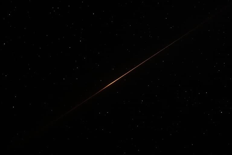 A hair-thin, barely visible amber line of light crossing diagonally through near-black deep space